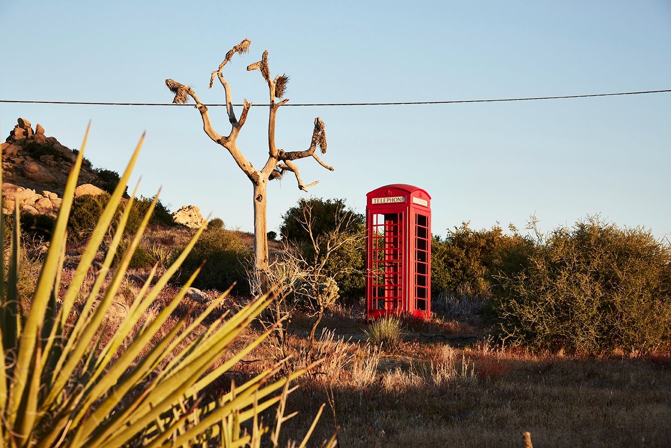 A red British telephone box in the high desert at ESCAPE — Pioneertown, California, golden hour