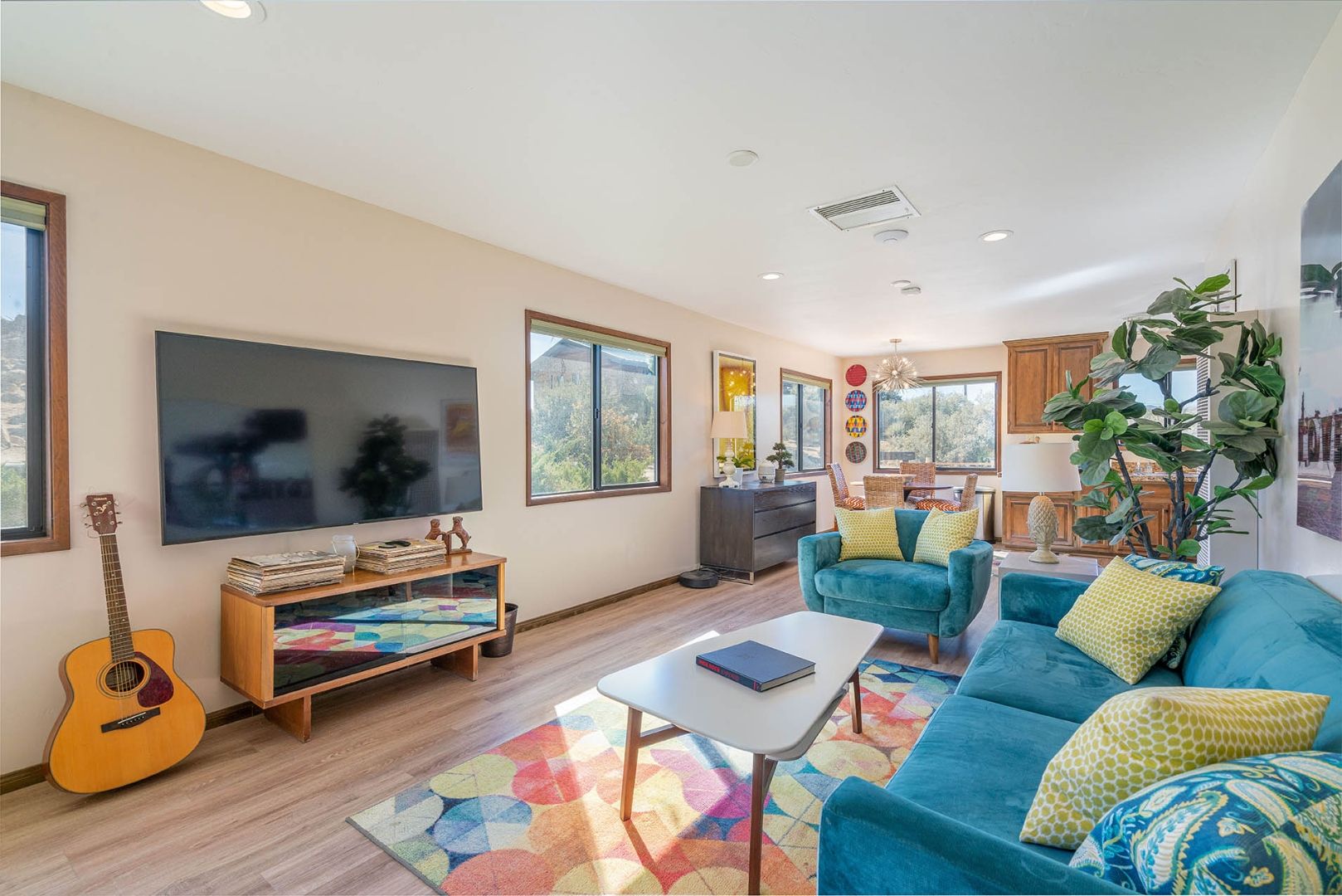 The Cottage living room at ESCAPE with teal sofas, a guitar, and desert windows