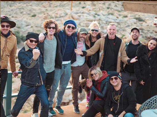 A songwriting camp group portrait at golden hour on the deck — ESCAPE, Pioneertown, California