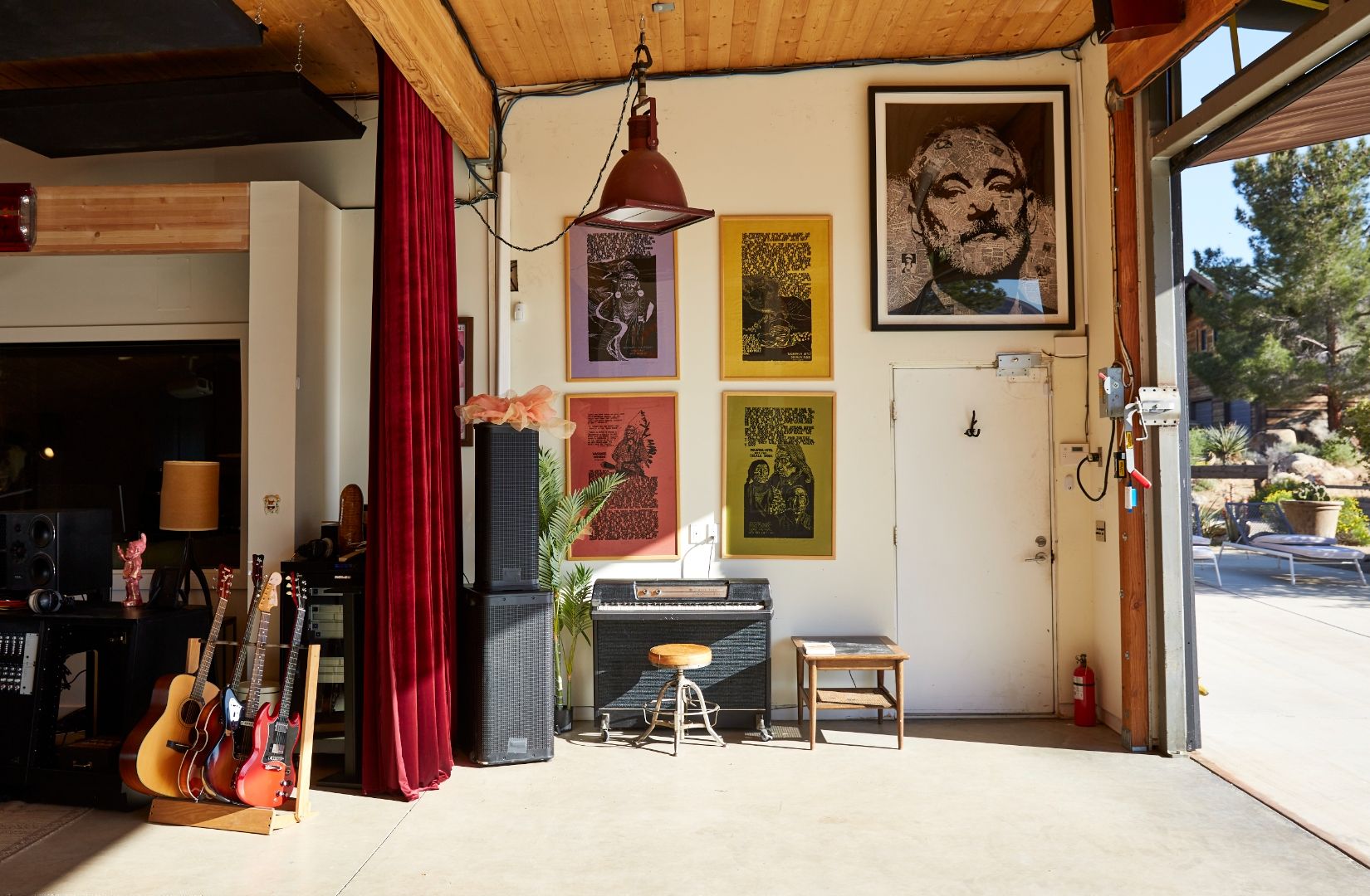 Studio One at ESCAPE — guitar rack, vintage amp, Bill Murray portrait and gig posters, doors open to the desert