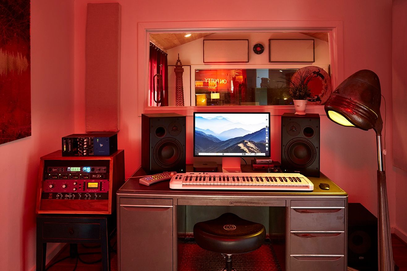 The Editing Suite at ESCAPE — pink room with desk, monitors, gear rack, and a window into Studio One