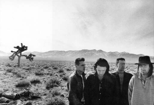 U2 standing in the Mojave Desert beside a Joshua tree, black and white